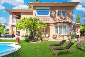 Ein zweistöckiges Haus mit Swimmingpool, Gartenmöbeln und einem gepflegten Garten.