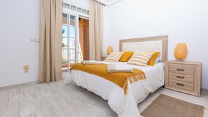 A bedroom with a bed, a bedside table, a lamp, and a window with curtains. - LXR Villa Elysée: 4 Bedrooms, Pool, and Amenities (AN)