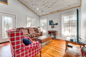 A living room with a sofa, a coffee table, a wooden desk, and a television.