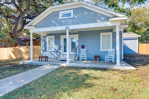 A two-story house with a covered porch, a front door, and a small front yard.
