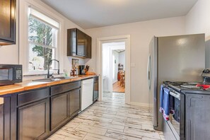 A kitchen with dark cabinets, a microwave, a sink, and a refrigerator.