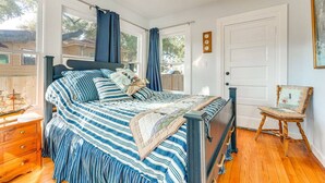Une chambre à coucher avec un lit, une table de chevet en bois, une chaise et un ventilateur de plafond.