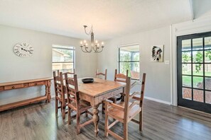 A dining area with a wooden table and chairs, a chandelier, and a clock on the wall. - Pet-Friendly Lockhart Home With Private Yard! (Lockhart)