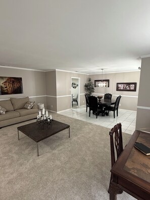 A living room with a sofa, coffee table, dining table with chairs, and a chandelier. - Peaceful Home spacious 4 Bedrooms in Savannah
STR 026567 (Savannah)