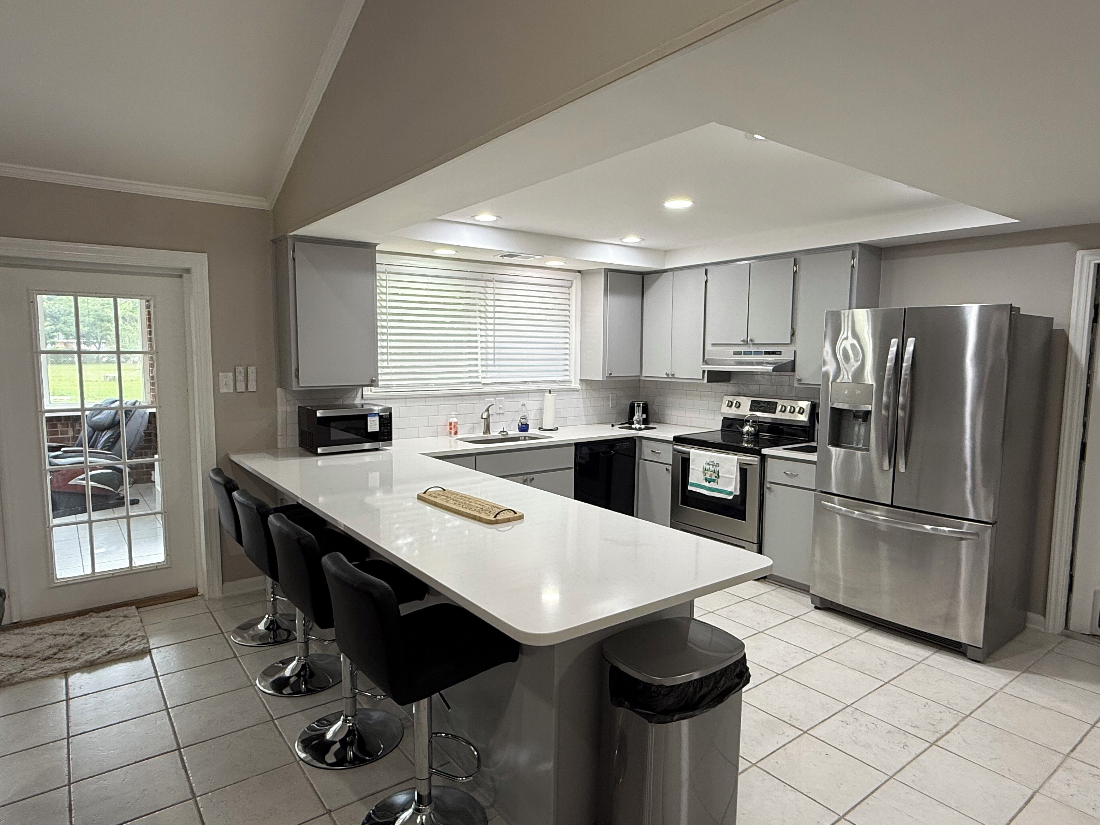 A modern kitchen with a central island, stainless steel appliances, and a view to the outside.
