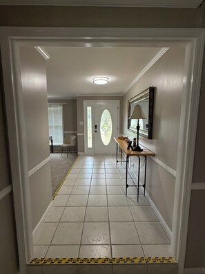 A hallway with a tiled floor, a door with a glass panel, a bench with a lamp, and a mirror on the wall. - Peaceful Home spacious 4 Bedrooms in Savannah
STR 026567 (Savannah)