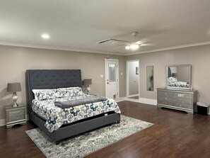 A bedroom with a large bed, a dresser, a mirror, and a ceiling fan. - Peaceful Home spacious 4 Bedrooms in Savannah
STR 026567 (Savannah)
