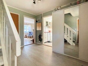 Un pasillo amplio con piso de madera, una escalera y vista a una cocina.