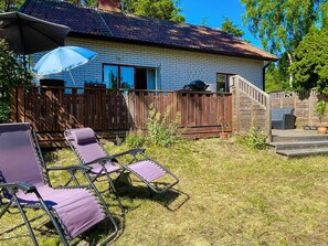 Una casa con fachada de ladrillo, una terraza de madera y una parrilla.