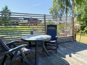 Un espace extérieur aménagé avec une table ronde et deux chaises, une clôture en bois et un lampadaire.