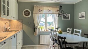A kitchen with a window, a dining table with chairs, and a clock on the wall. - 6 Person Holiday Home in Byxelkrok (Byxelkrok)
