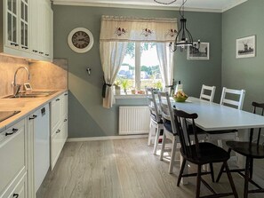 A kitchen with a window, a dining table with chairs, and a clock on the wall. - 6 Person Holiday Home in Byxelkrok (Byxelkrok)