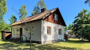 A two-story wooden house with a sloped roof, a small porch, and a visible chimney. - 6 Person Holiday Home in Byxelkrok (Byxelkrok)