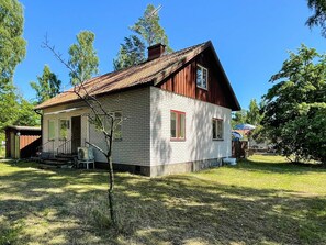 A two-story wooden house with a sloped roof, a small porch, and a visible chimney. - 6 Person Holiday Home in Byxelkrok (Byxelkrok)