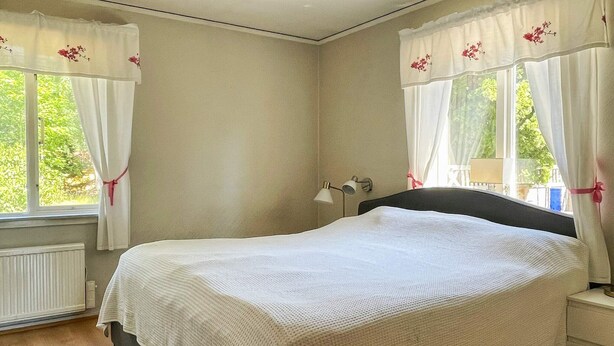 A bedroom with a bed, a nightstand, a lamp, and a window with curtains. - 6 Person Holiday Home in Byxelkrok (Byxelkrok)
