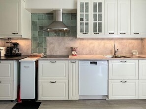 A modern kitchen with white cabinetry, a stainless steel range hood, a coffee maker, and a built-in dishwasher. - 6 Person Holiday Home in Byxelkrok (Byxelkrok)