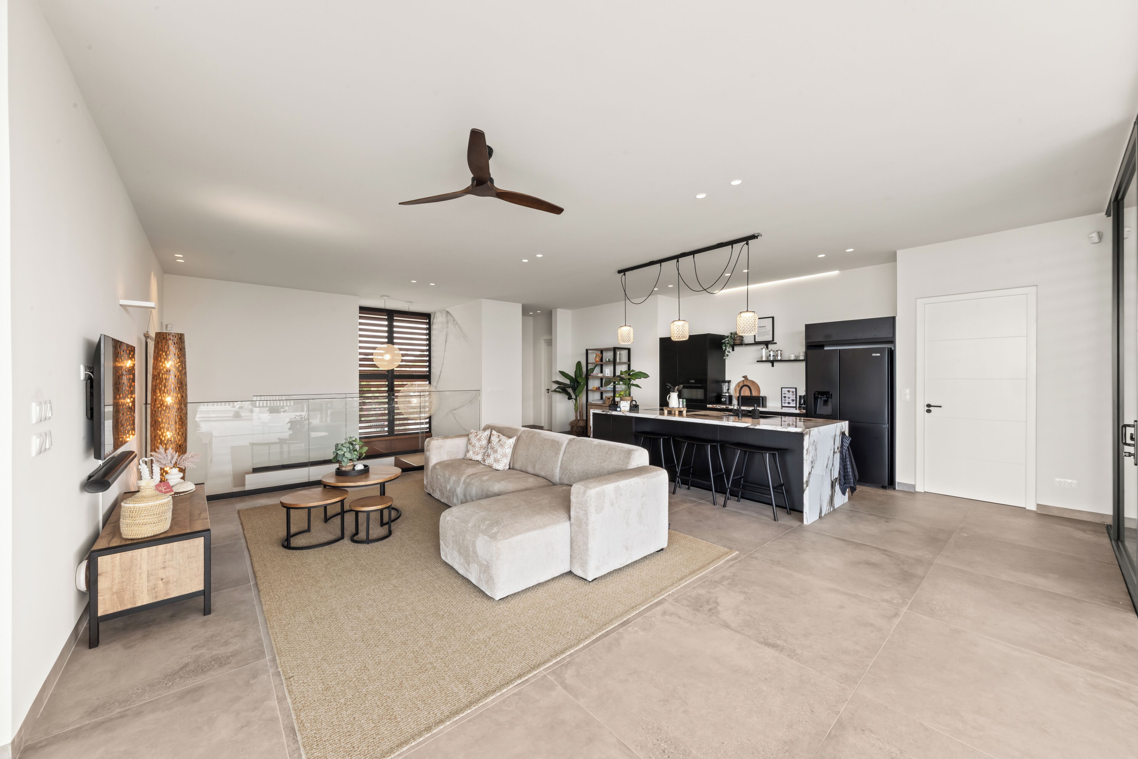 Uma sala de estar moderna com sofá, mesa de centro e área de jantar, com cozinha ao fundo.
