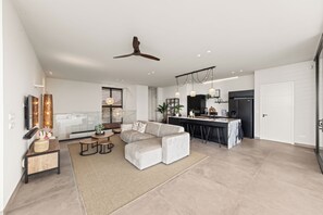 A modern living room with a sofa, coffee table, and a dining area with a kitchen in the background. - Villa Quatrosol - an exclusive private resort under the sun! (Jan Thiel)