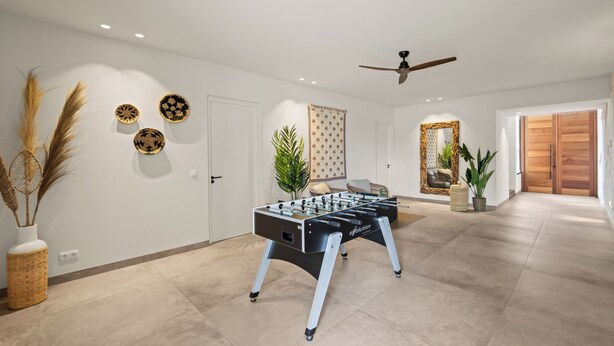 A spacious room with a foosball table, a ceiling fan, and a large mirror. - Villa Quatrosol - an exclusive private resort under the sun! (Jan Thiel)
