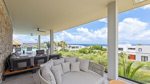 A modern outdoor seating area with a view of the ocean and a pool. - Villa Quatrosol - an exclusive private resort under the sun! (Jan Thiel)