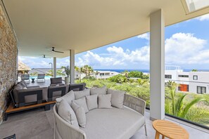 Uma área de estar moderna ao ar livre, com vista para o oceano e uma piscina.