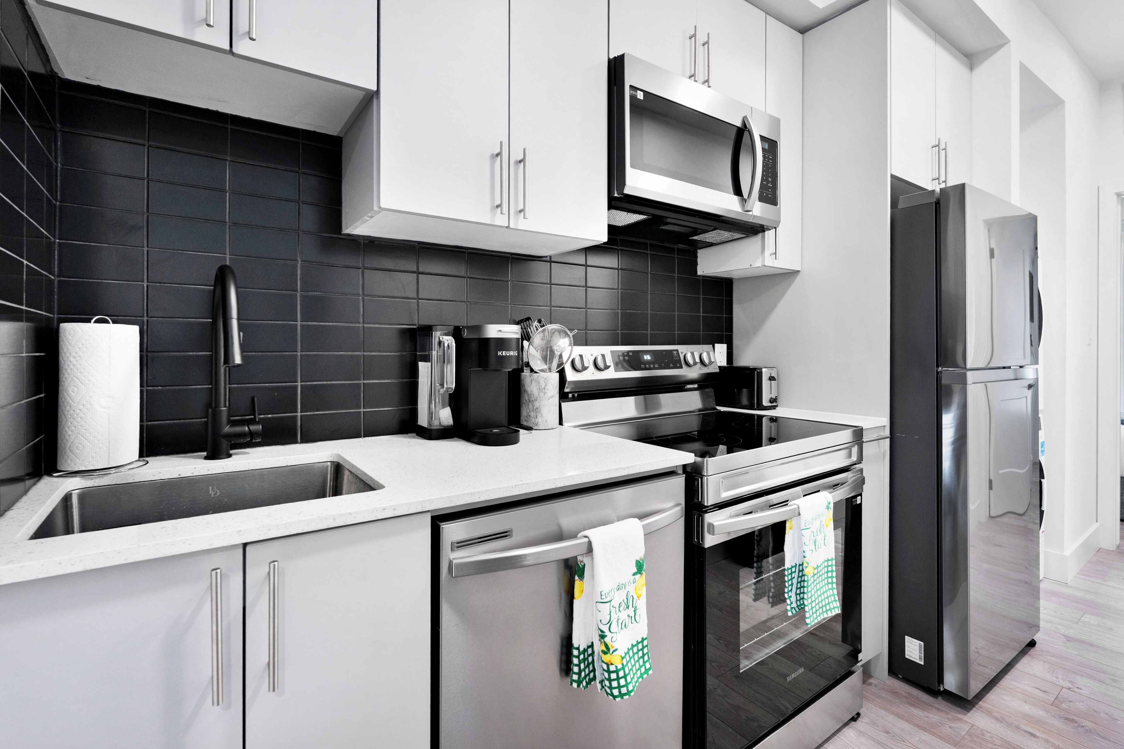 A modern kitchen with stainless steel appliances, a microwave, and a refrigerator.