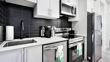 A modern kitchen with stainless steel appliances, a microwave, and a refrigerator.