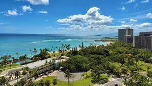 En kuststad med en klar himmel, en strand och en parkeringsplats omgiven av grönska.