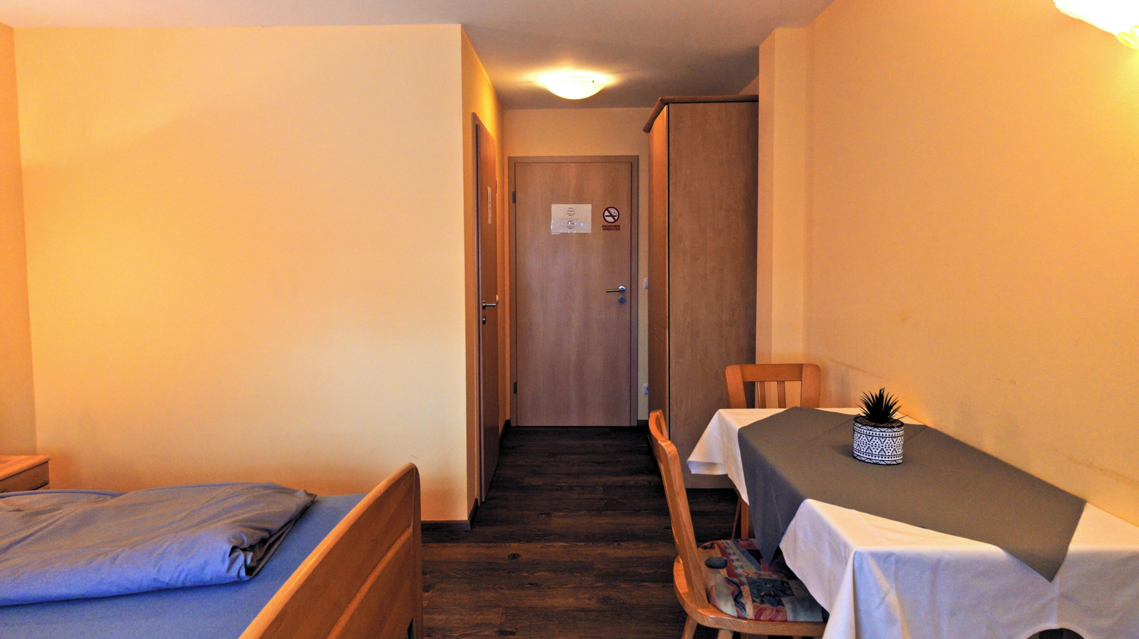 Un pasillo estrecho con una cama a la izquierda y una mesa con una silla a la derecha.