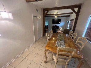 A dining area with a wooden table, white chairs, and a patterned table runner. - Charming 3-bedroom house in serene Mims (Mims)