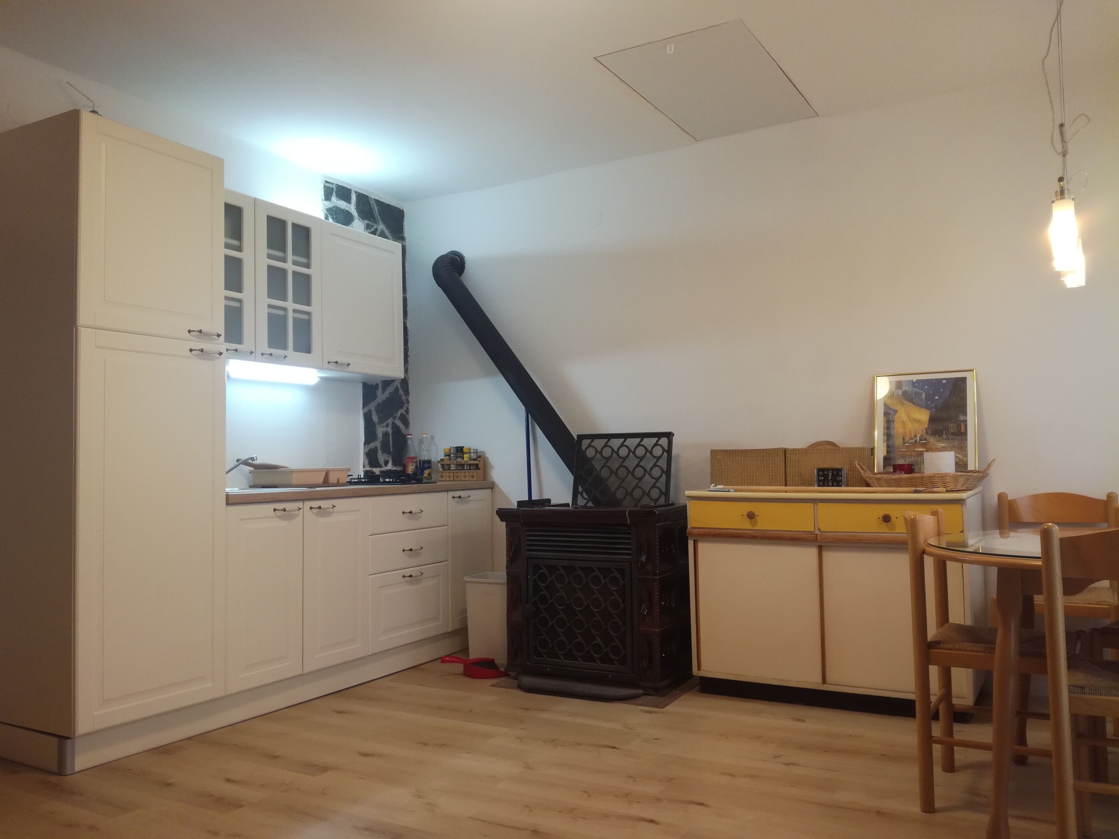 A compact kitchen with white cabinets, a black stove, and a dining area with a wooden table and chairs.