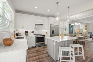 A modern kitchen with white cabinets, stainless steel appliances, and a central island.