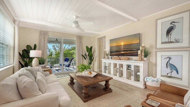 A living room with a sofa, coffee table, and a TV mounted on the wall. - Luxury Waterfront Home in Resort Community Sea and Sand at Hunters Point (Cortez)