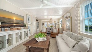 A spacious living area with a wooden coffee table, a sofa, and a dining area with chairs. - Luxury Waterfront Home in Resort Community Sea and Sand at Hunters Point (Cortez)