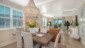 A dining area with wicker furniture, a chandelier, and a view of the outdoors. - Luxury Waterfront Home in Resort Community Sea and Sand at Hunters Point (Cortez)
