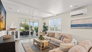 A living room with a sofa, coffee table, and a view to the outside. - Luxury Home in Resort Community Private Pool Game & Room Baydream Believer at Hunters Point (Cortez)