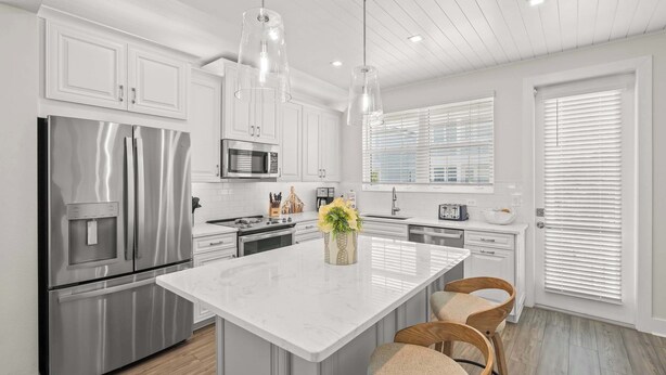 A modern kitchen with stainless steel appliances, a marble island, and pendant lighting. - Luxury Home in Resort Community Private Pool Game & Room Baydream Believer at Hunters Point (Cortez)