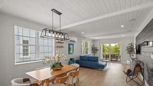 A spacious living area with a dining table, chairs, a blue sofa, and a hanging light fixture. - Luxury Waterfront Home in Resort Community Sea Salt at Hunters Point (Cortez)