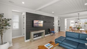 A modern living room with a fireplace, a sofa, a coffee table, and a TV mounted on the wall. - Luxury Waterfront Home in Resort Community Sea Salt at Hunters Point (Cortez)