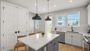 A modern kitchen with white cabinetry, a central island, and pendant lighting. - Luxury Waterfront Home in Resort Community Sea Salt at Hunters Point (Cortez)