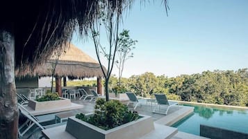 Un área de piscina al aire libre con sillones de descanso y una estructura de techo de paja.