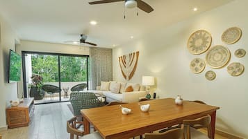 Una sala de estar moderna con comedor, un conjunto de sofás, una mesa de centro y decoración en la pared.