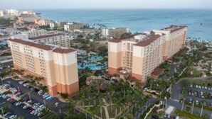 Un resort con varias construcciones, una zona de piscina y vista al océano.