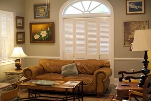 Ein Wohnzimmer mit braunem Ledersofa, einem Couchtisch, einer Lampe und einem Fenster mit Rollläden.