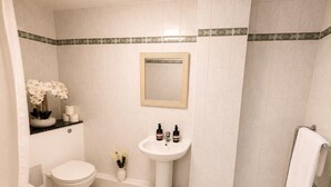 Een badkamer met toilet, wastafel, spiegel en douche.