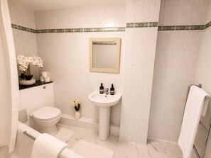 Ein Badezimmer mit Toilette, Waschbecken, Spiegel und Duschbereich.