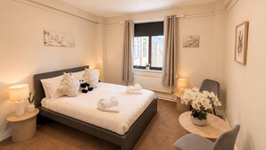 Hotelkamer met een bed, een rond tafel met stoel, een raam met gordijnen en kunst aan de muur.