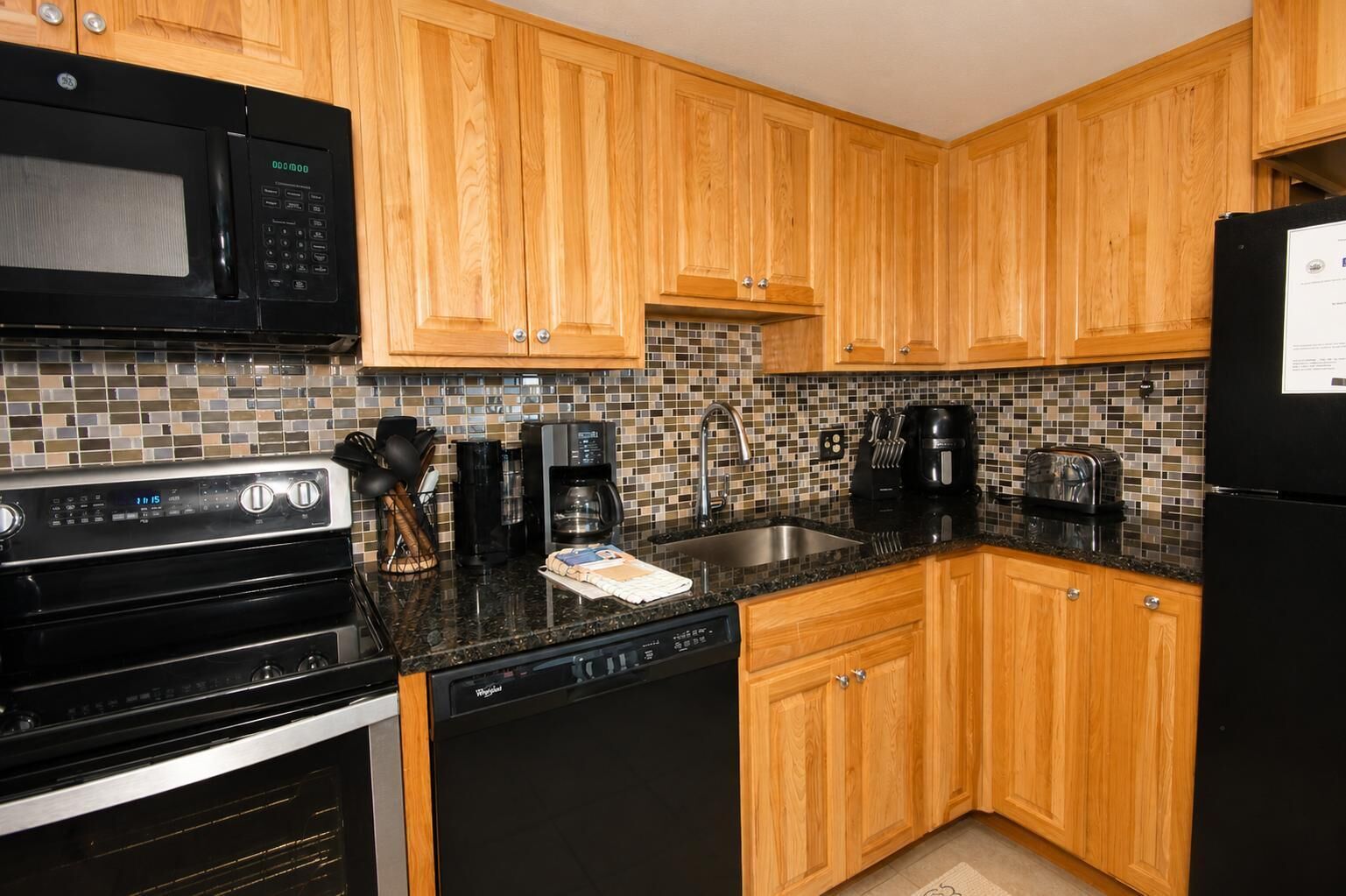 A kitchen with wooden cabinets, a microwave, a stove, a dishwasher, and a refrigerator.