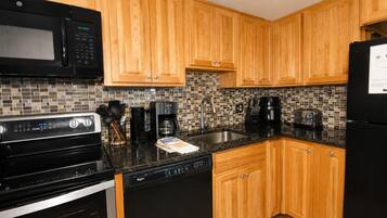 A kitchen with wooden cabinets, a microwave, a stove, a dishwasher, and a refrigerator.