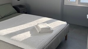 Ein Schlafzimmer mit einem Bett, einem Nachttisch, einem Fenster mit Meerblick und einer Deckenleuchte.